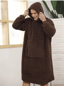 Male model wearing an oversized brown sherpa hooded blanket in a cozy room.