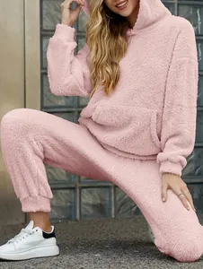 Model wearing a pink fuzzy hoodie and pants two-piece lounge set in a stylish urban setting