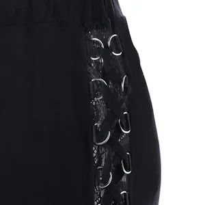 Detail van een punkbroek met vetersluiting aan de zijkant en zwart kanten inzetstuk