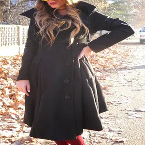 Detailed view of women's black asymmetrical wool coat worn in an outdoor setting