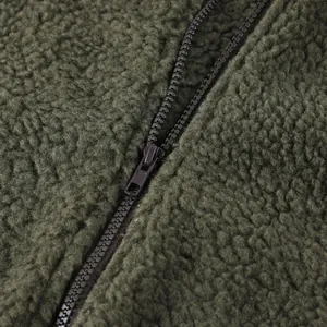 Dettaglio ravvicinato del materiale in pile felpato verde militare e della robusta zip
