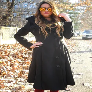 Elegant black wool coat with an irregular hem shown in a scenic outdoor autumn setting