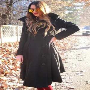 Detail of women's black double-sided wool coat with asymmetrical hem in autumn park