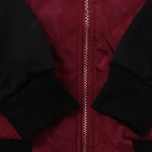 Detailansicht einer burgunderroten Steppjacke mit Reißverschluss und schwarzen Rippbündchen