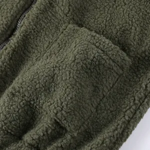 Dettaglio ravvicinato della morbida texture in pile sherpa e della tasca della giacca verde