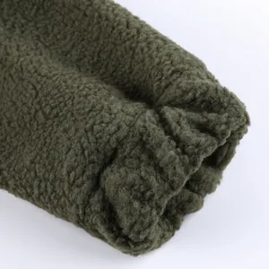 Dettaglio ravvicinato del polsino elasticizzato e del pile sherpa di una giacca verde oliva.