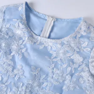 Close-up detail showing the elegant white floral lace embroidery and zipper of a blue dress.
