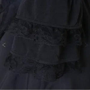 Détail d'une robe vintage noire avec de la dentelle à plusieurs niveaux et volants.