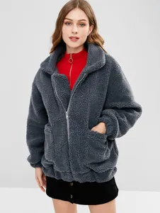 Dettaglio di una giacca in peluche antracite con cerniera e ampie tasche frontali.
