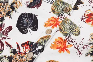 Macro view of a tropical leaf print fabric featuring vintage natural wooden button detail