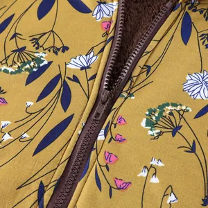 Macro detail of mustard floral jacket showing brown zipper and warm fleece lining