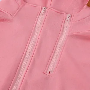 Dettaglio macro di una felpa con cappuccio rosa da donna con doppia cerniera unica.
