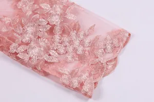 Detailed macro shot of pink lace fabric with exquisite floral embroidery for evening dress.