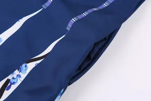 Makro-Detailaufnahme eines marineblauen Vintage-Kleides mit Blumenmuster und Tasche