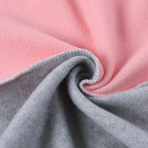 Primo piano del morbido tessuto in pile bifacciale rosa e grigio con cuciture taglia-cuci