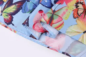Detailed close-up of vibrant butterfly print on a light blue summer dress hemline
