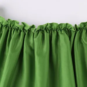 Détail en gros plan du décolleté à volants vert épaules dénudées d'une robe rétro