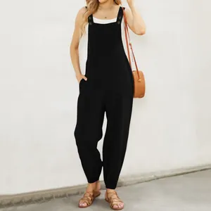 Full-length view of a black cotton linen jumpsuit featuring button straps and front pockets.