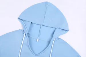 Dettaglio ravvicinato di una felpa con cappuccio azzurra da donna con lacci bianchi.