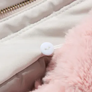 Macro view of white button and soft pink faux fur collar attachment on winter coat