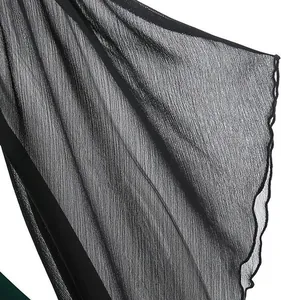 Detail shot showing the texture of a black pleated chiffon sleeve with wavy edge