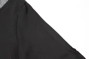 Close-up detail of black dress with silver sequined collar and cutout shoulder.