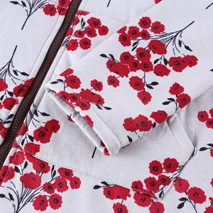 Close-up detail of white hooded jacket with red floral pattern and brown resin zipper