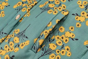Detailed macro view showing pocket seam and yellow floral print on teal winter coat fabric