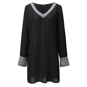 Dettaglio di abito nero a maniche lunghe con scollo a V e polsini in paillettes argento