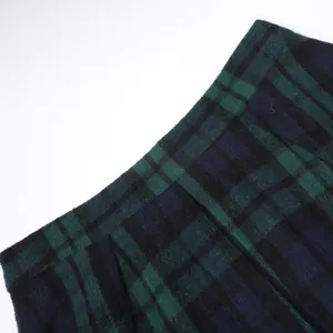 Detalle de una falda de tablas a cuadros verde oscuro que muestra el tejido