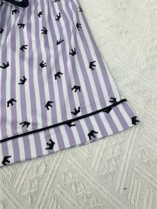 Gros plan d'un pyjama rayé violet et blanc orné d'un motif de couronne noire détaillée