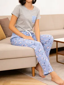 Women's two-piece floral pajama set with short-sleeve top and long pants in a home setting