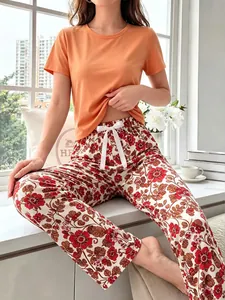 Detailed view of cozy women's floral pajama set featuring a bright orange short-sleeved top