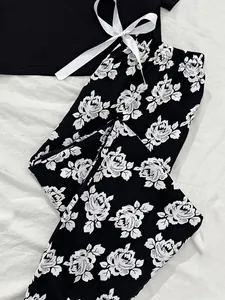Close-up detail of floral pyjama pants showing white rose patterns and decorative bow