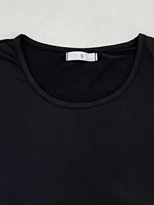 Close-up detail view of black women's pajama top neckline with white size S label