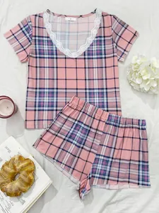 Vista dettagliata di un pigiama a quadri rosa da donna con scollo a V in pizzo e pantaloncini.