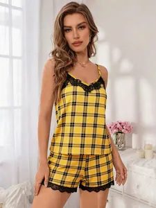 Modella che indossa un set pigiama a quadri gialli con bordo in pizzo nero in camera da letto