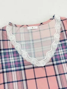 Dettaglio ravvicinato di un top pigiama a quadri rosa con scollo a V e pizzo bianco