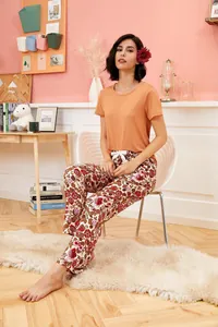 Two-piece summer pajama set with orange top and floral print trousers for women
