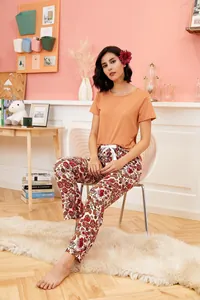 Lifestyle view of a woman wearing orange short-sleeved pajama top and floral print pants
