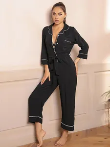 Full view of women's black long-sleeved jumpsuit pajamas with elegant white piping trim