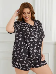 Plus size black pajama set featuring a short-sleeve shirt and shorts with pink bow prints