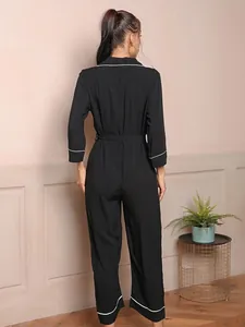 Back view of black long-sleeved jumpsuit pajamas featuring elegant white piping details.