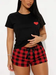 Close-up view of a women's black pajama set with heart patch and red plaid shorts
