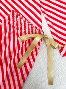 Close-up of red and pink striped pajama pants with a golden satin ribbon bow detail