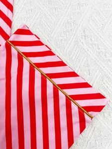 Detailed macro shot of red and pink striped festive pajama fabric featuring gold piping trim