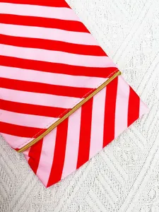 Macro detail of red and pink striped Christmas pajamas with elegant gold piping finish.