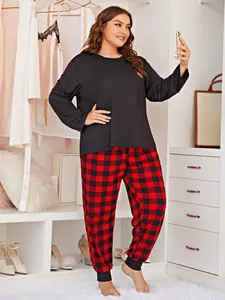 Plus size woman in black long-sleeved top and red plaid pajama pants taking a selfie