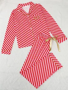 Detailed view of red striped Christmas pajamas with gold piping and blessed embroidery