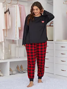 Detail view of cozy plus size pajama set with heart print top and red plaid pants.
